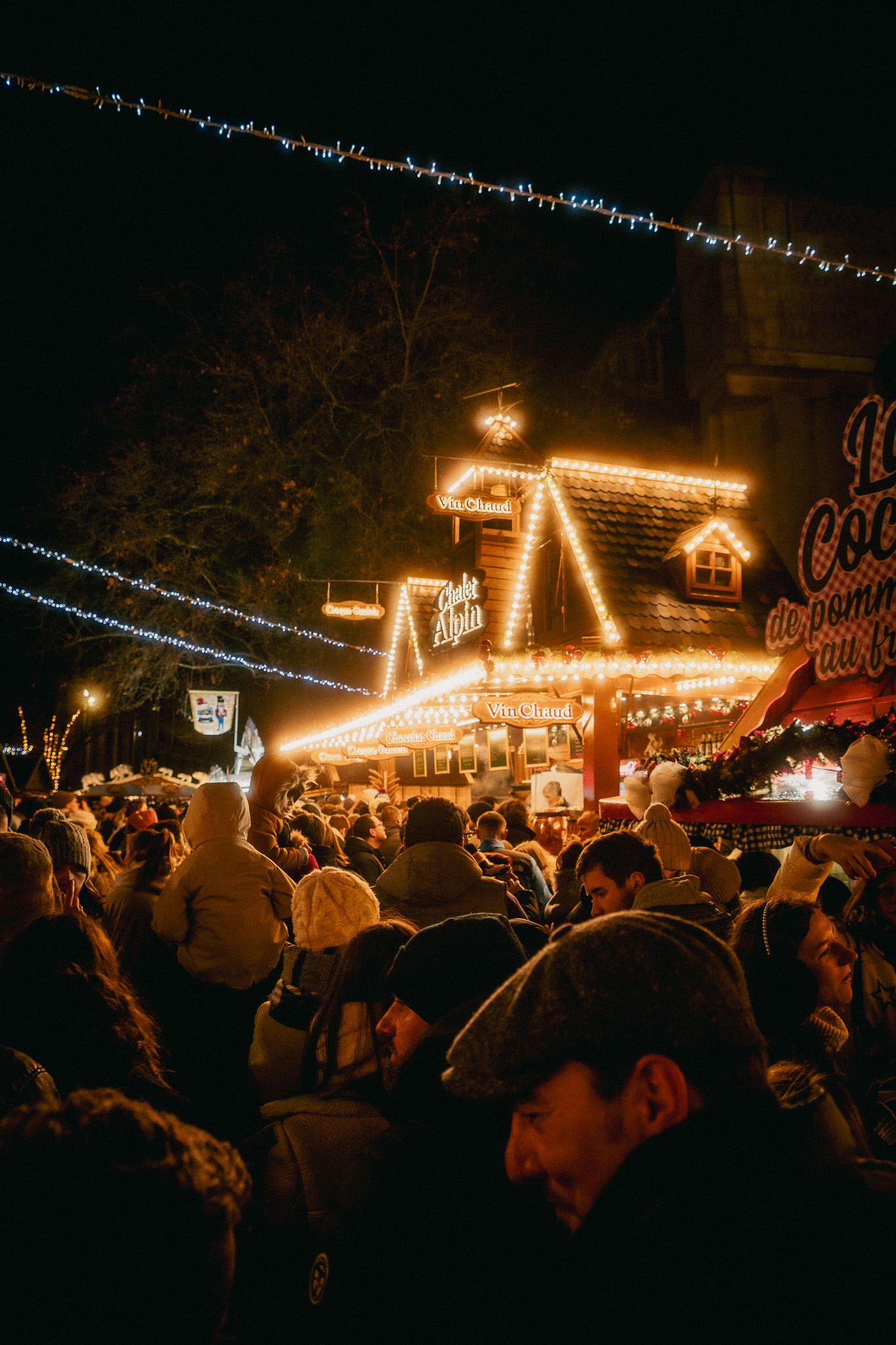Visiteurs devant les chalets illuminés du Village de Noël de Lille